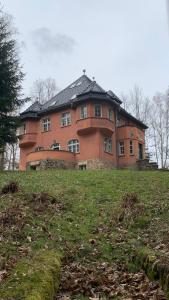 duży ceglany budynek na szczycie trawiastego wzgórza w obiekcie Baltic Home w Polanicy Zdroju