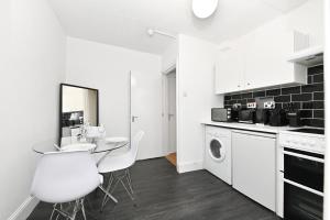 a kitchen with white appliances and a table and chairs at Covent Garden & Soho, Cosy & Cool, Spacious Apartment in London