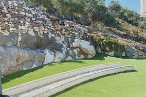 a stone wall next to a field of green grass at Panormos Beach Hotel Skopelos in Panormos Skopelos