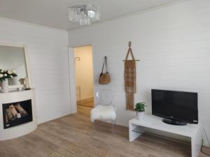 a living room with a flat screen tv and a chair at Yyterin valkoinen huoneisto 14A talo B 21 in Pori