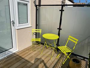 duas cadeiras amarelas e uma mesa num alpendre em The Alvaros Apartment em Southend-on-Sea