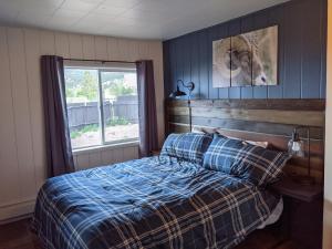 a bedroom with a bed with a plaid blanket and a window at Slackwater Inn in Buena Vista
