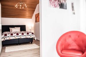 a red chair in a bedroom with a bed at Apartment PourinGraz für Kunst- und Tennisliebhaber in Graz