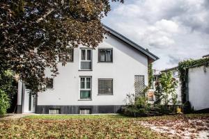 ein weißes Haus mit schwarzen Fenstern und einem Hof in der Unterkunft Apartment PourinGraz für Kunst- und Tennisliebhaber in Graz