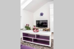 a living room with a white table and a tv at Apartment PourinGraz für Kunst- und Tennisliebhaber in Graz