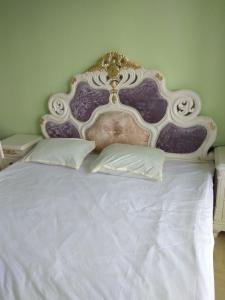 Una cama blanca con cabecero púrpura y blanco en Апартаменты Талиана Бич курорта Елените, en Elenite