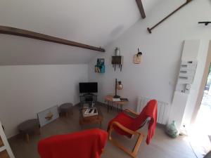 Péaule的住宿－Ty Sau Hiol, La Moniclair，客厅配有红色椅子和电视