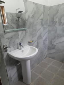 a bathroom with a white sink and a shower at Family Holiday Inn in Badulla