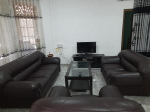 een woonkamer met 2 leren banken en een tv bij Family Holiday Inn in Badulla