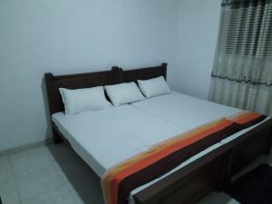 a bed with white sheets and pillows in a room at Family Holiday Inn in Badulla