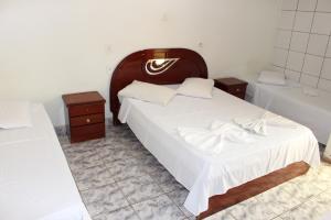 a bedroom with two beds and two night stands at Bica Pau Hotel in Caldas Novas
