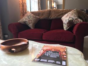 a book and a bowl on a table in front of a couch at The Cheese Room, self-contained cosy retreat in the Quantock Hills in Bridgwater