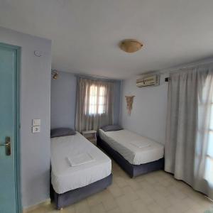 two beds in a small room with a window at Voula's House in Skiathos Town