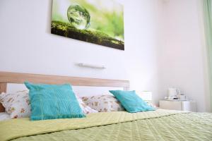 a bedroom with a bed with green sheets and blue pillows at Rooms Vilma close to Rab City in Rab
