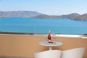 a table with two glasses and a candle on a balcony at Elounda Heights (Adults Only) in Elounda