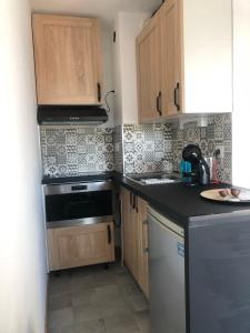 a kitchen with wooden cabinets and a sink and a stove at Appart. F2 apercu Port de Santa Lucia St Raphaël in Saint-Raphaël