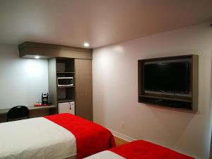 ein Hotelzimmer mit einem Bett und einem Flachbild-TV in der Unterkunft Motel Chez Nous in Laval