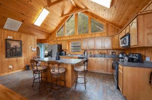 a kitchen with wooden cabinets and a island with bar stools at BareFoot Cabin cabin in Sevierville