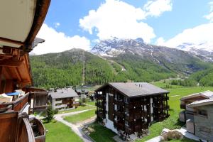 un immeuble dans un village avec des montagnes en arrière-plan dans l'établissement Aramis, à Saas-Fee