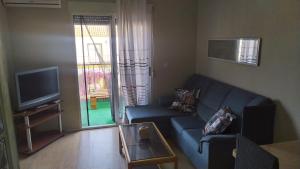 ein Wohnzimmer mit einem blauen Sofa und einem TV in der Unterkunft Alojamiento en Urb La Marina in San Fulgencio