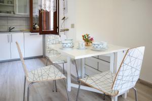 - une table et des chaises blanches dans la cuisine dans l'établissement Apartment Azzuro Porto Ottiolu, à Porto Ottiolu