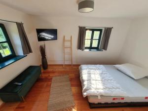 a bedroom with a bed and two windows and a ladder at Ferienhaus am Dachsberg, Bayerischer Wald in Haselbach