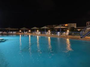 a large swimming pool at night with chairs and umbrellas at Chalet with backyard in North Coast near Marina & New Alamein الساحل الشمالي العلمين in El Alamein