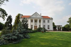 ein großes weißes Haus mit einem grünen Hof in der Unterkunft Restauracja - Hotel Pałacowa in Rogowo