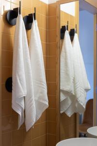 a bathroom with white towels hanging on a wall at Na Travessa Suítes in Porto +64 photos