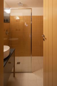 a bathroom with a glass shower and a sink at Na Travessa Suítes in Porto