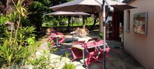 un grupo de sillas y mesas con sombrilla en Hostellerie du Parc en Labarthe-Inard