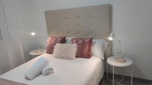 una camera da letto con un letto bianco con cuscini e 2 lampade di Casa Gascona con parking, wifi y netflix gratis!! By DeLabra Apartments a Oviedo