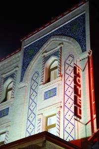 a building with a neon sign in front of it at Sultan Hotel Boutique in Samarkand