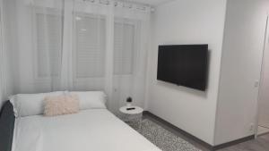 una camera da letto bianca con un letto e una TV a schermo piatto di Casa Gascona con parking, wifi y netflix gratis!! By DeLabra Apartments a Oviedo