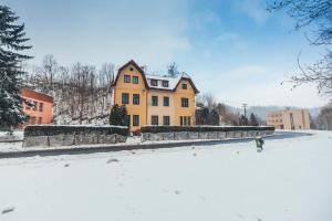 a large yellow house in the snow with a yard at Schupplerova vila in Hoštejn