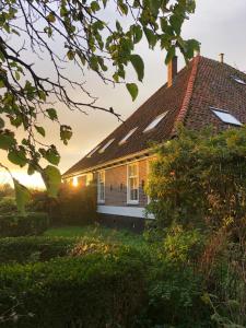 a house with the sun shining on the roof at B&B De Pauw - Country Home Cooking in Graft