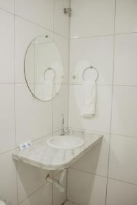 a white bathroom with a sink and a mirror at Pousada Alpes in Triunfo