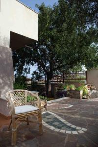 a wicker chair sitting on a patio with a tree at Casa Marzane in Cala Gonone