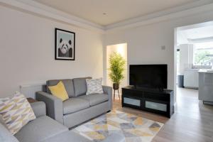 a living room with a couch and a flat screen tv at Spacious Three Bedroom House - Free Parking & Wifi in Chelmsford