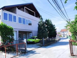 une voiture verte garée devant une maison blanche dans l'établissement Dino Sarajevo Apartment, à Sarajevo