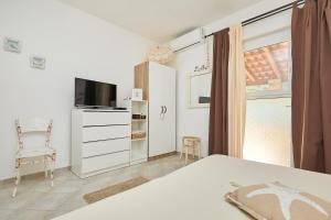 1 dormitorio con 1 cama, TV y silla en Studio Dolores-apartment by the sea, en Maranovići