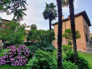 a garden with pink flowers and palm trees in front of a building at villa berghinz in Venice-Lido