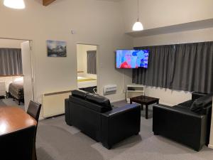 sala de estar con muebles negros y TV de pantalla plana en ASURE Townsman Motor Lodge, en Invercargill