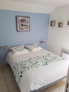 um quarto com uma cama branca com flores azuis em charmante maison proche des alignements em Carnac
