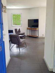 a living room with a tv and a chair and a table at Gîte mon plaisir in Carnac