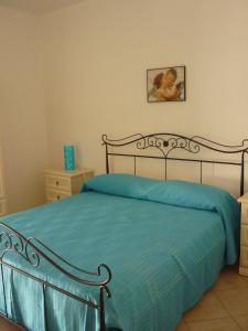 ein Schlafzimmer mit einem Bett mit einer blauen Decke in der Unterkunft Appartamento Luna in San Vito lo Capo