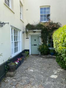 Heathcote House في Milborne Saint Andrew: بيت ابيض بباب ازرق وبعض النباتات