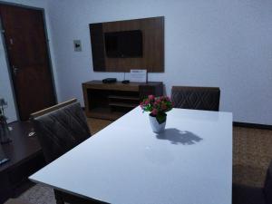 een witte tafel met een vaas met bloemen erop bij Apartamento Bento Residence in Uruguaiana