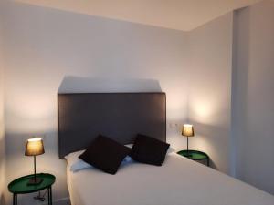 1 dormitorio con 1 cama blanca y 2 lámparas en Apartamentos Casa La Rambla, en San Esteban de Pravia