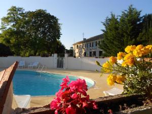 a swimming pool with flowers next to a house at Domaine de la gare M - anciennement Logis de La Garenne in Mortagne-sur-Gironde